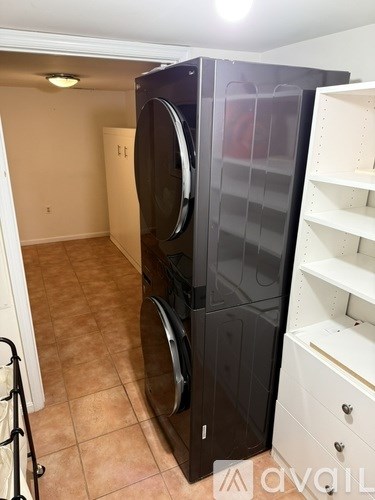 A black refrigerator in a kitchen with a white shelf.