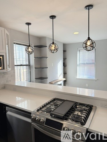 A modern kitchen with a stove top oven and pendant lights.