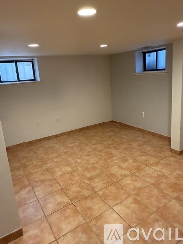 A room with tiled flooring and two windows.