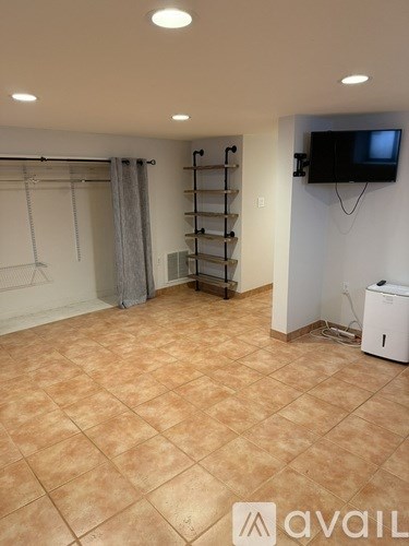 A room with a tiled floor and a television mounted on the wall.