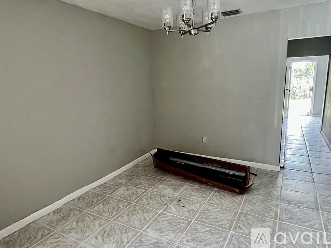 A room with a chandelier, a piano, and a door leading outside.