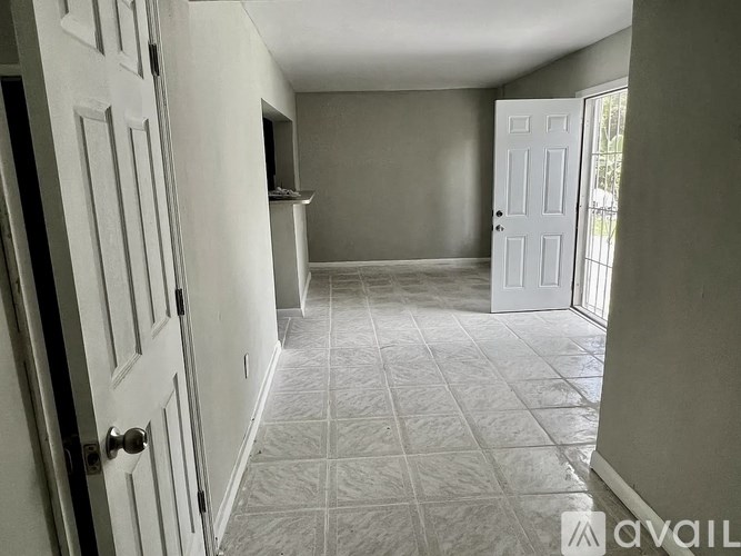 A hallway with a tiled floor and white doors.