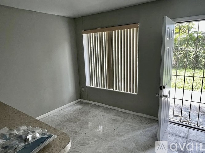 A room with a marble floor and a window with vertical blinds.