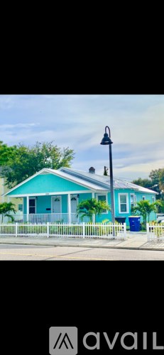 A blue house with a white picket fence and a lamp post in front.