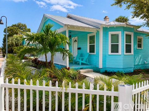 A blue house with a white picket fence and a lamp post in front.