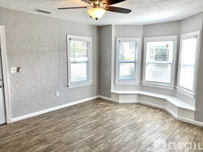 A room with a ceiling fan and three windows.