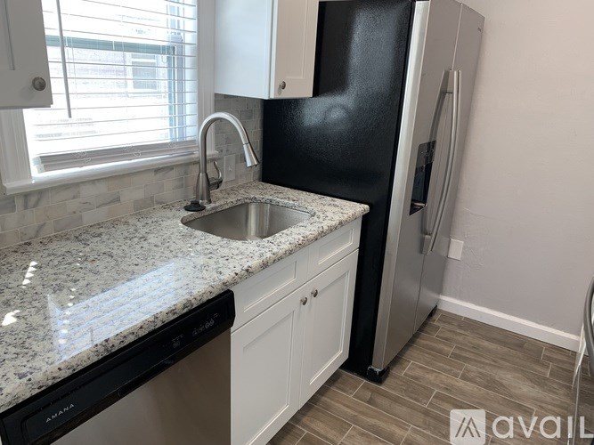 A kitchen with granite countertops and a black refrigerator.