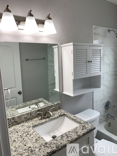 A bathroom with granite countertops and a white toilet.
