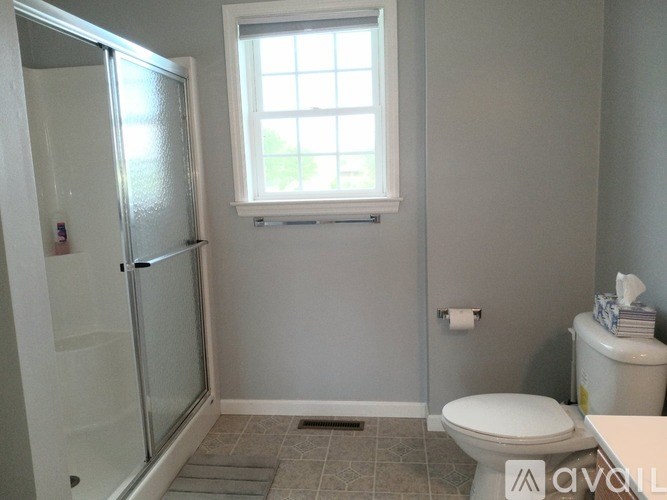 A bathroom with a toilet, a window, and a glass door.