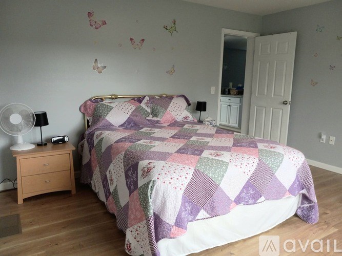A bedroom with a bed, a nightstand, and a wall decal of butterflies.