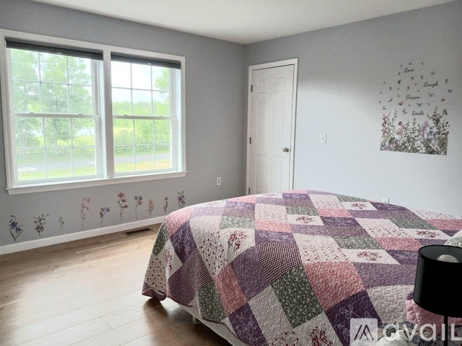 A bedroom with a bed, window, and wall art.