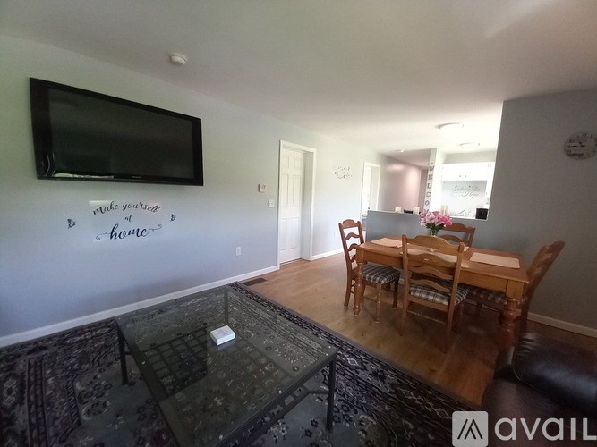 A living room with a glass table and a television mounted on the wall.