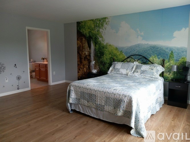 A bedroom with a large bed and a wall mural of a forest.