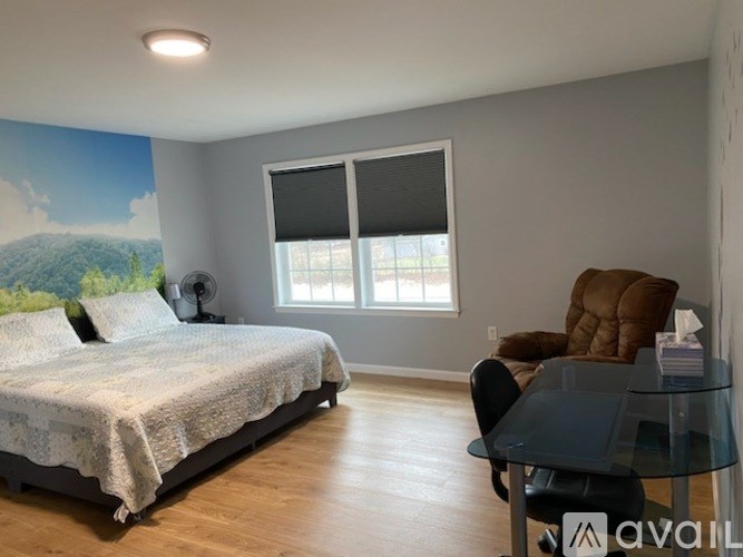 A bedroom with a bed, chair, and a wall mural.