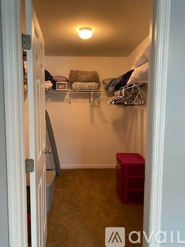 A small room with a bed and a red stool.