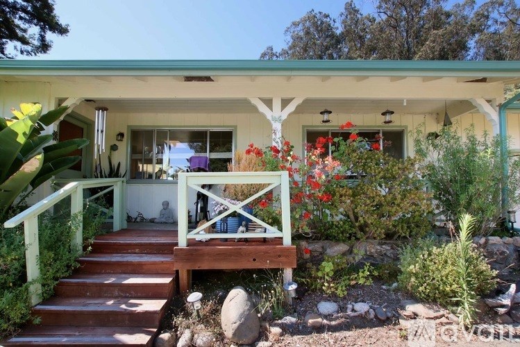 A white house with a green roof and a wooden porch.