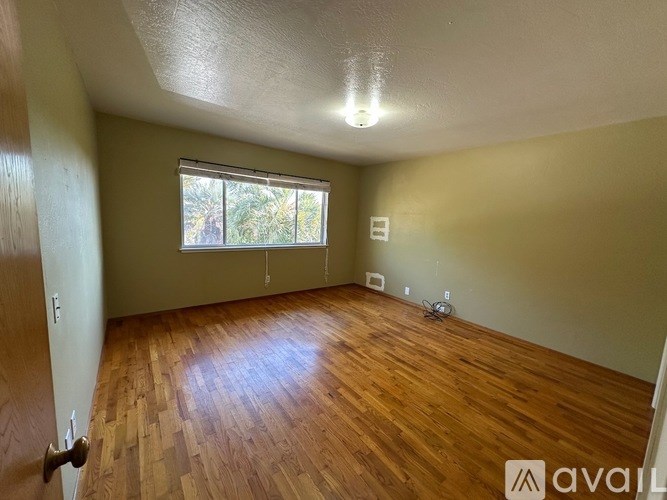 A room with wooden flooring and a window letting in natural light.