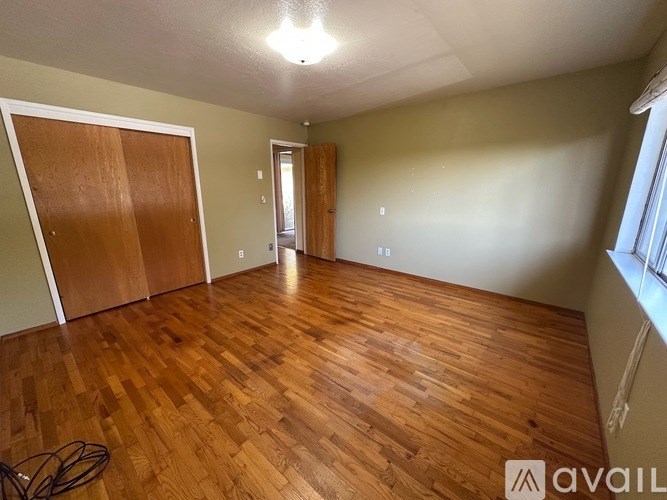 A room with wooden flooring and a door on the left.