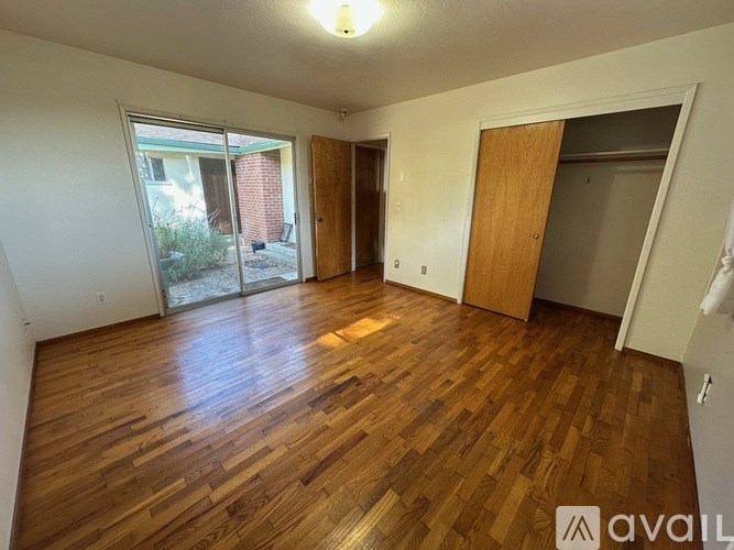 A room with wooden flooring and a sliding glass door.