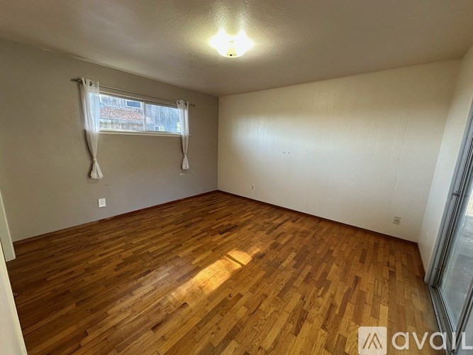 A room with wooden flooring and a window with curtains.