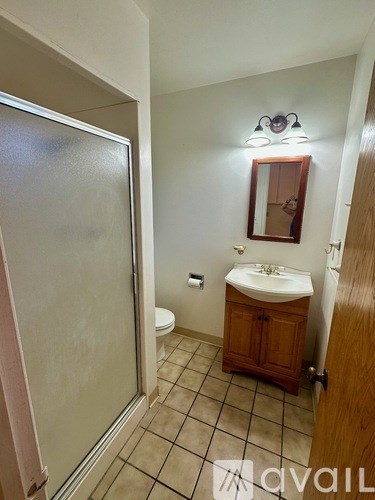 A bathroom with a toilet, sink, and mirror.