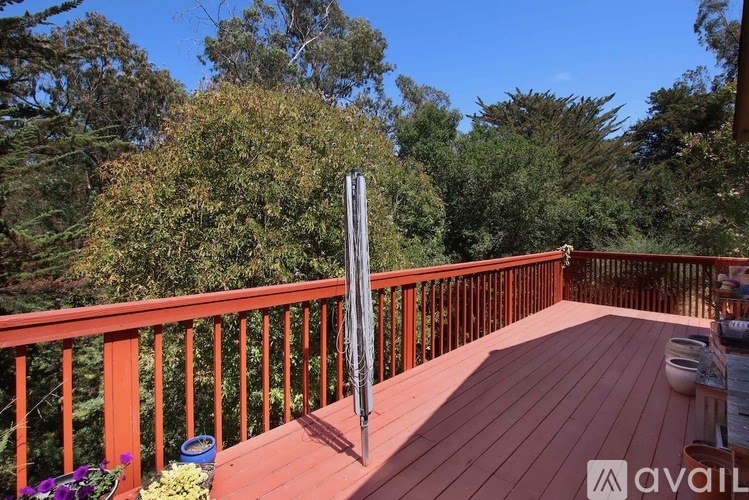 A wooden deck with a railing and a pole in the middle.