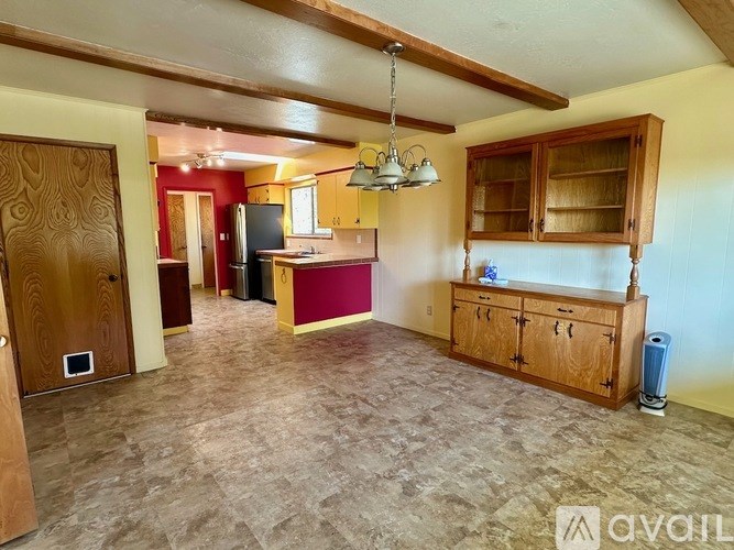 A kitchen with wooden cabinets and a red wall.