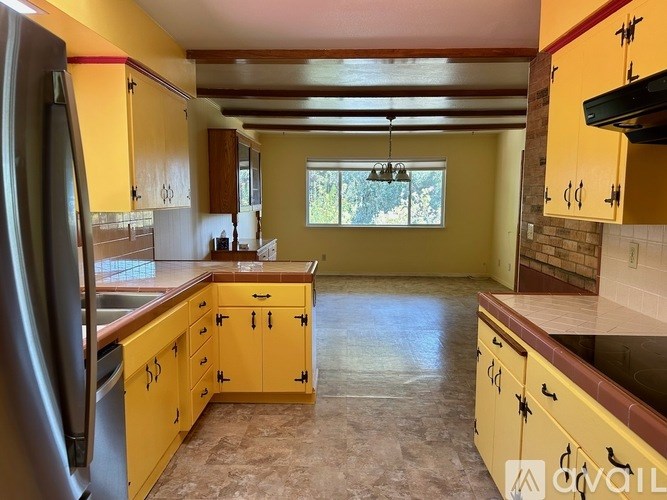 A kitchen with yellow cabinets and a refrigerator.