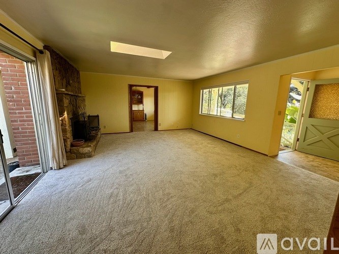 A spacious room with a carpeted floor and a fireplace.