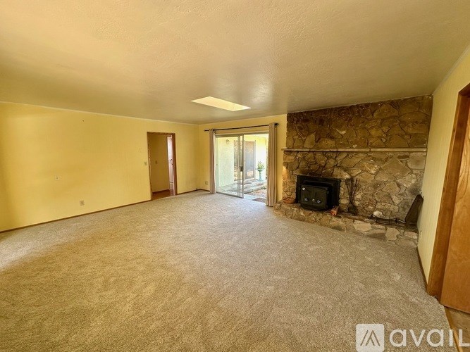 A living room with a stone fireplace and a carpeted floor.