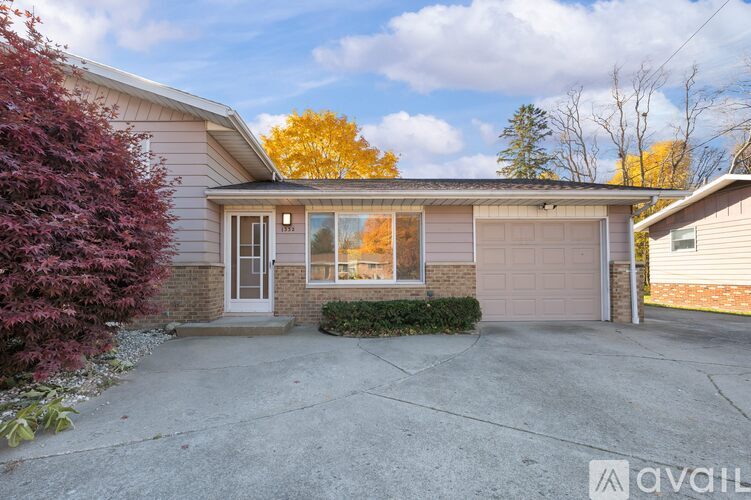 A house with a driveway and a tree in front.