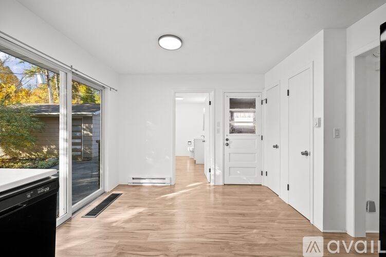 A spacious, empty room with wooden floors and white walls.