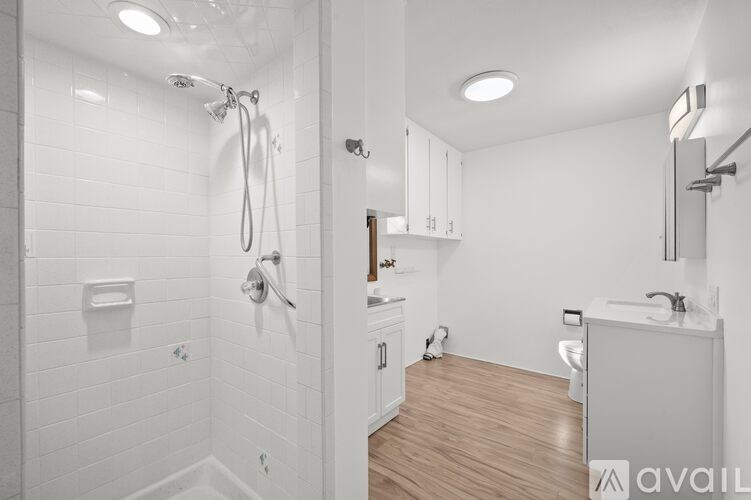 A white bathroom with a walk-in shower and wooden floors.