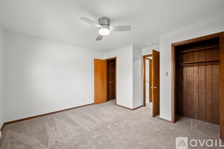 A room with a ceiling fan and three doors.