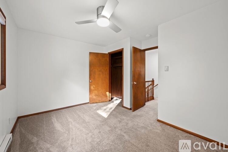 A room with a carpeted floor and a ceiling fan.