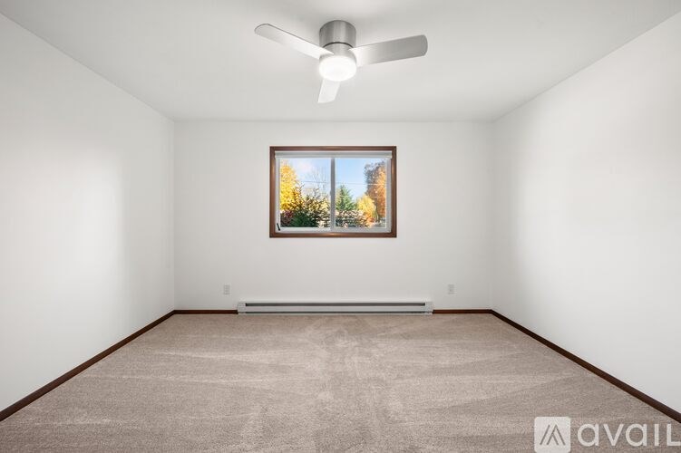 A room with a carpeted floor and a ceiling fan.