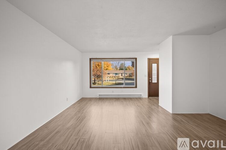 A large empty room with a painting on the wall and a door on the right.