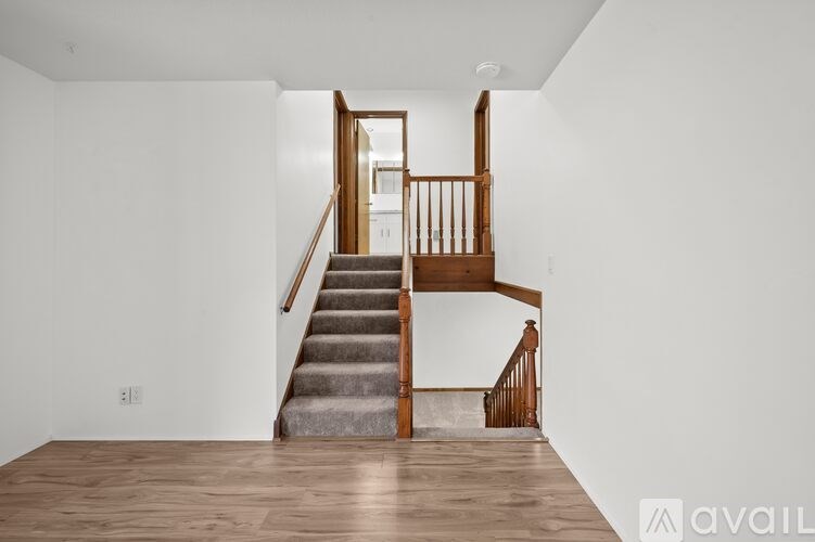A wooden staircase with a carpeted runner leads up to a landing with a door.
