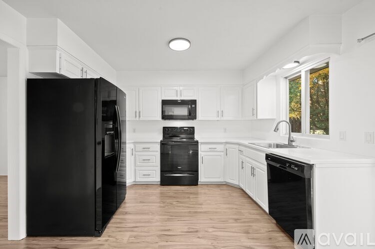 A kitchen with black appliances and white cabinets.