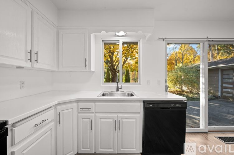 A kitchen with white cabinets and a black dishwasher.