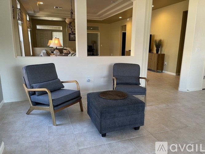 Two chairs and ottoman are in a room with a mirror.