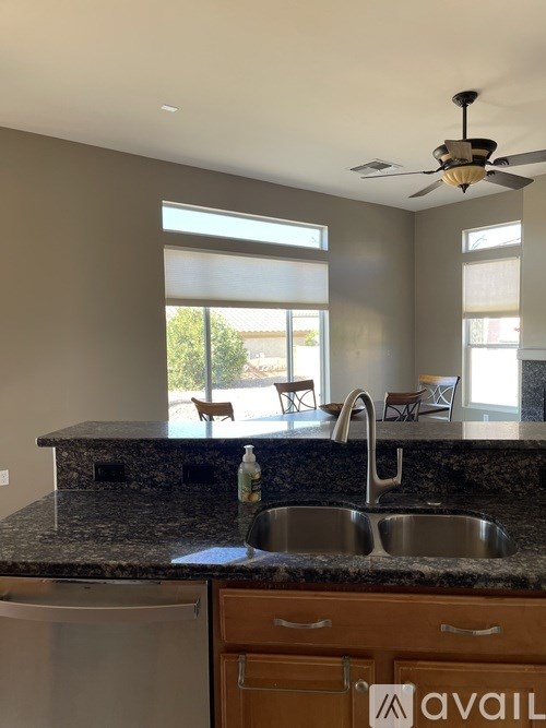 A kitchen with a granite countertop and a stainless steel sink.