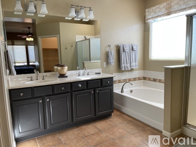 A bedroom with a chair, a dresser, and a bed.