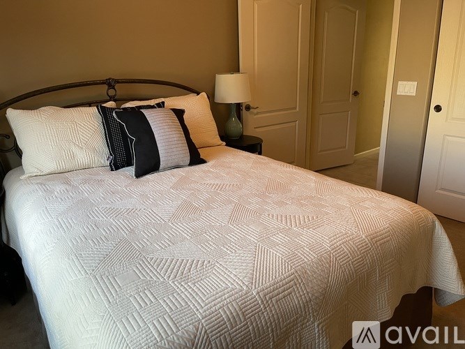 A bed with a white comforter and two pillows with black and white stripes.