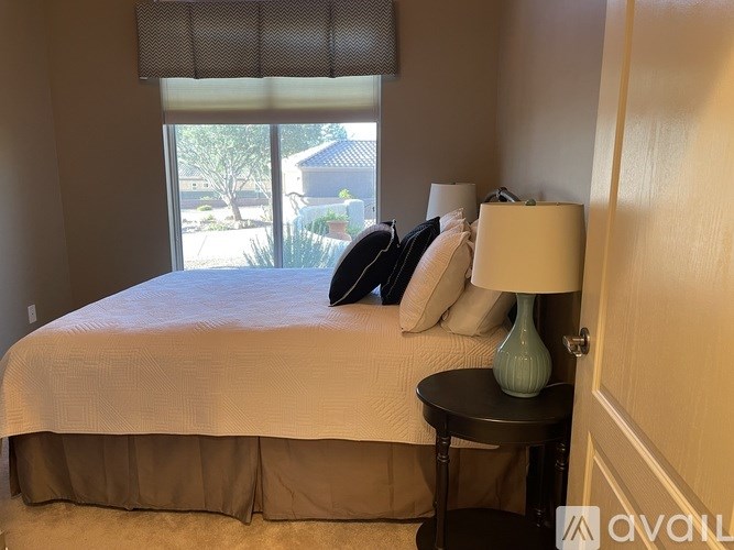 A bedroom with a bed, a lamp, and a window with blinds.