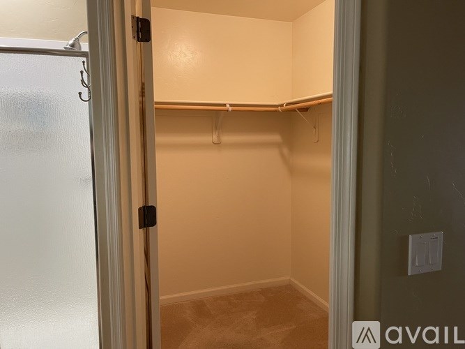 A small, empty kitchen pantry with a white door and a white refrigerator.