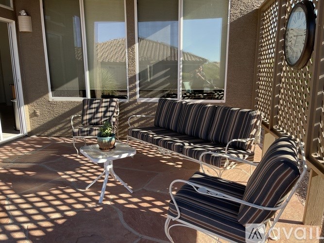 A patio with a table, chairs, and a clock on the wall.