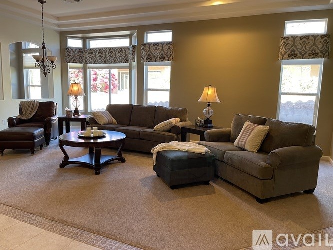 A living room with a brown sofa, a black coffee table, and a chandelier.