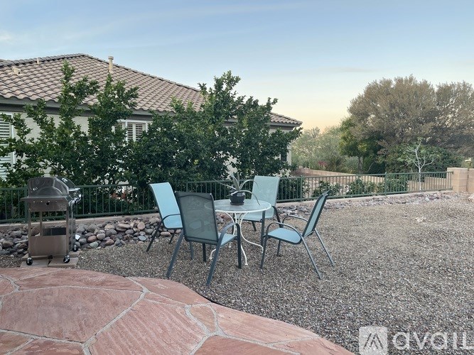 A patio with a table and chairs is set up in front of a house.