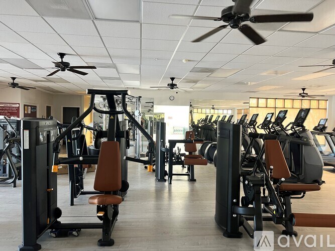 A gym with a variety of equipment including treadmills, weights, and a fan.